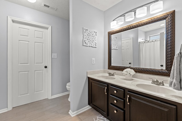 bathroom featuring vanity, toilet, a textured ceiling, and hardwood / wood-style floors