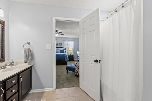 bathroom featuring wood-type flooring, curtained shower, vanity, a textured ceiling, and ceiling fan