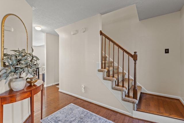 stairway with a textured ceiling and hardwood / wood-style flooring