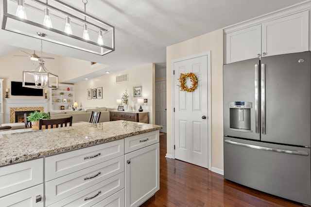 kitchen with white cabinets, light stone countertops, dark wood-type flooring, stainless steel refrigerator with ice dispenser, and decorative light fixtures