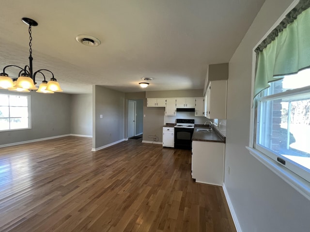 kitchen with white cabinetry, electric range, sink, hanging light fixtures, and a chandelier