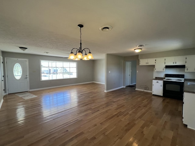 kitchen featuring white electric range oven, dark wood-type flooring, pendant lighting, white cabinets, and a chandelier