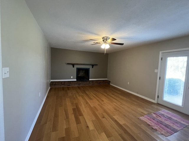 unfurnished living room with a fireplace, a textured ceiling, light hardwood / wood-style flooring, and ceiling fan