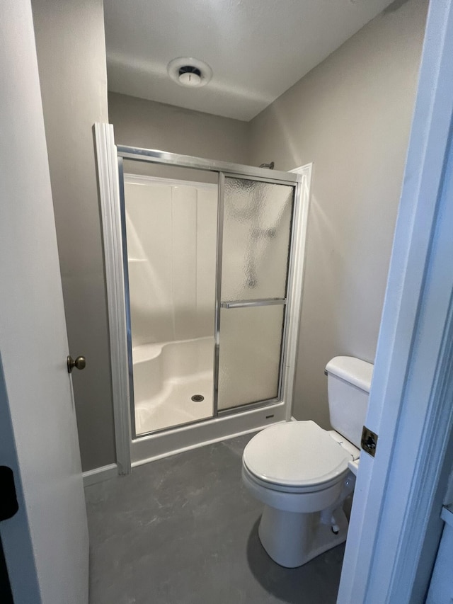 bathroom with toilet, walk in shower, and concrete floors