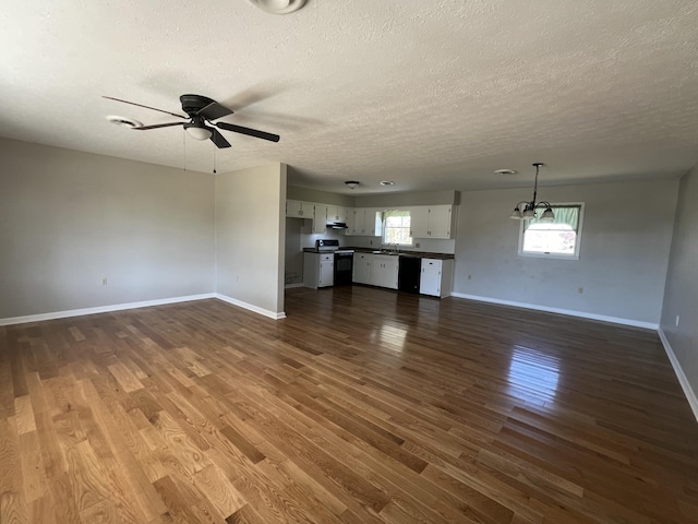 unfurnished living room with dark hardwood / wood-style floors, ceiling fan, and a textured ceiling