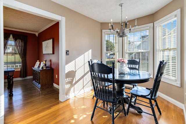 dining area with an inviting chandelier, crown molding, hardwood / wood-style flooring, and plenty of natural light