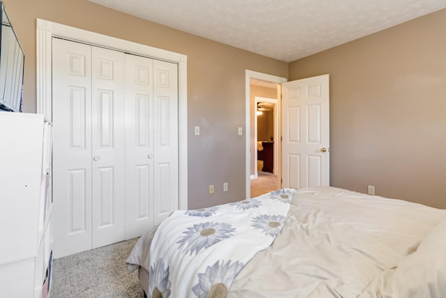 bedroom featuring light carpet, a textured ceiling, and a closet