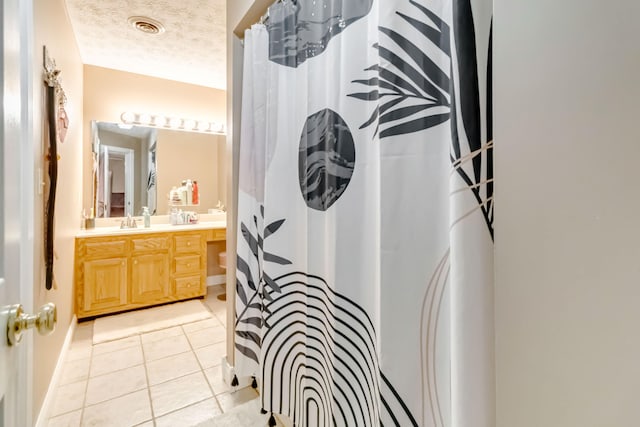 bathroom featuring vanity, a shower with shower curtain, a textured ceiling, and tile patterned floors