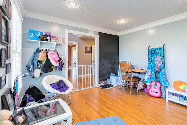 recreation room with crown molding, a textured ceiling, and wood-type flooring