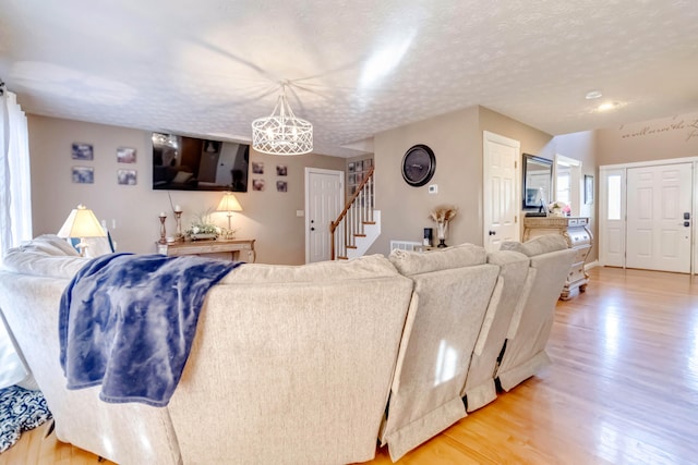 living room featuring an inviting chandelier, a textured ceiling, and light wood-type flooring