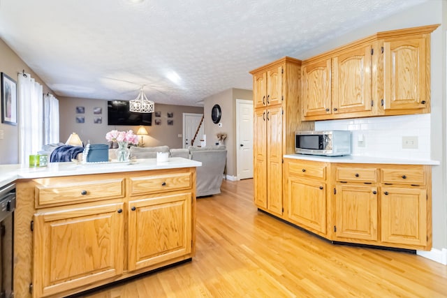 kitchen featuring decorative backsplash, a textured ceiling, light wood-type flooring, and dishwasher