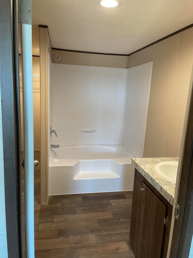 bathroom featuring  shower combination, vanity, a textured ceiling, and wood-type flooring