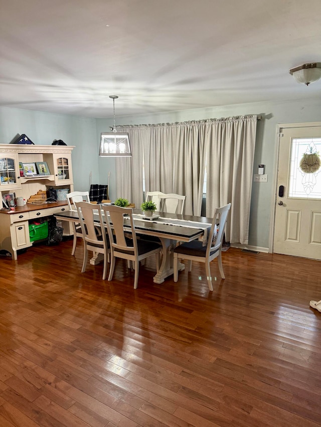 dining space with dark wood-type flooring and an inviting chandelier