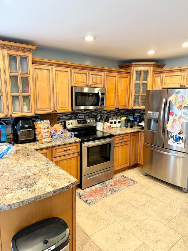 kitchen featuring light stone countertops, stainless steel appliances, and decorative backsplash