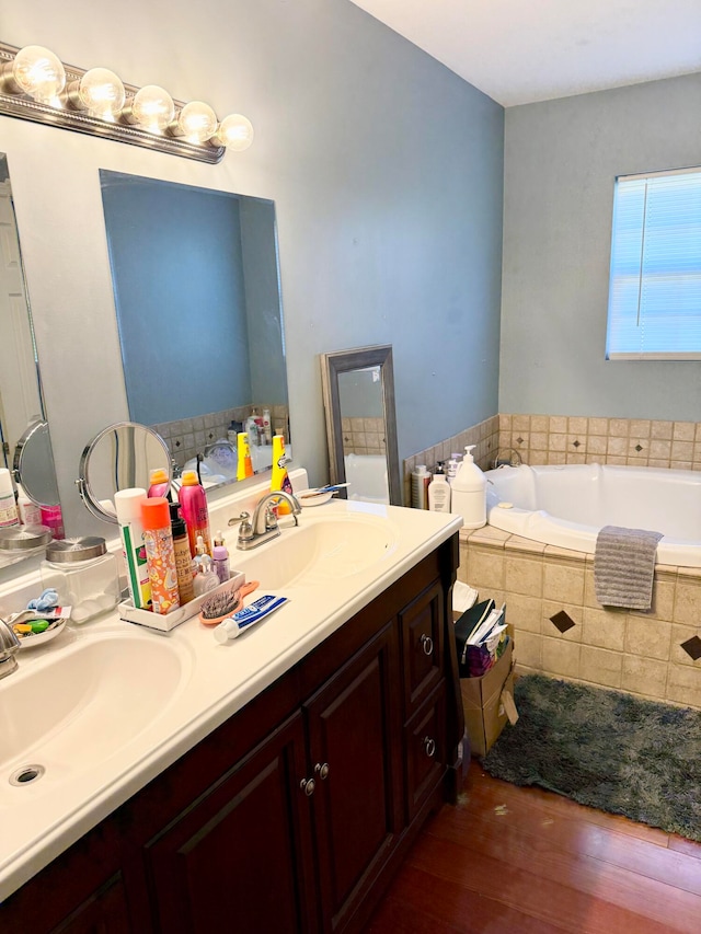 bathroom featuring vanity, hardwood / wood-style floors, and a relaxing tiled tub