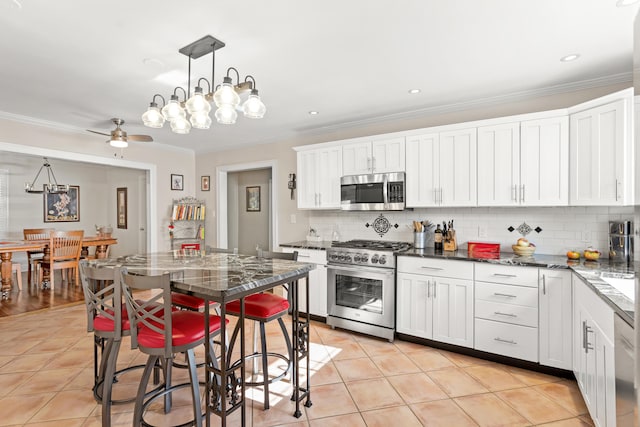 kitchen featuring white cabinetry, dark stone countertops, appliances with stainless steel finishes, and pendant lighting