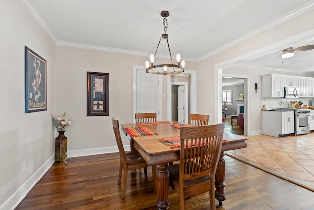 dining area featuring crown molding, wood-type flooring, and ceiling fan with notable chandelier