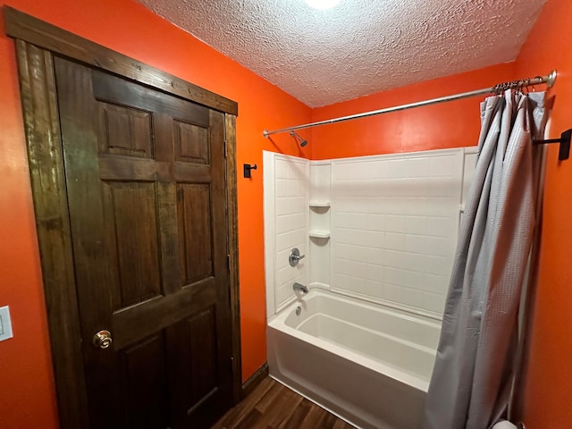 bathroom with a textured ceiling, shower / bathtub combination with curtain, and wood-type flooring