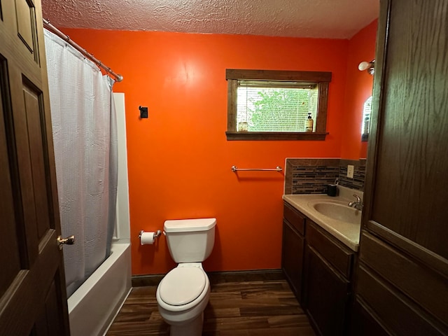 full bathroom with hardwood / wood-style flooring, toilet, shower / bath combo with shower curtain, vanity, and a textured ceiling