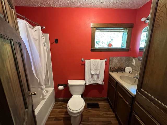 full bathroom featuring hardwood / wood-style flooring, toilet, shower / tub combo, vanity, and a textured ceiling