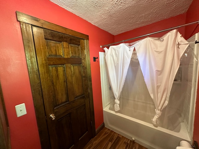 bathroom with a textured ceiling, shower / bath combo, and wood-type flooring