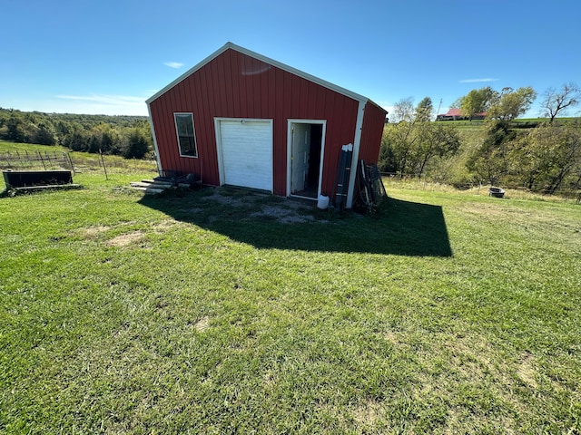 view of outbuilding featuring a rural view, a garage, and a lawn