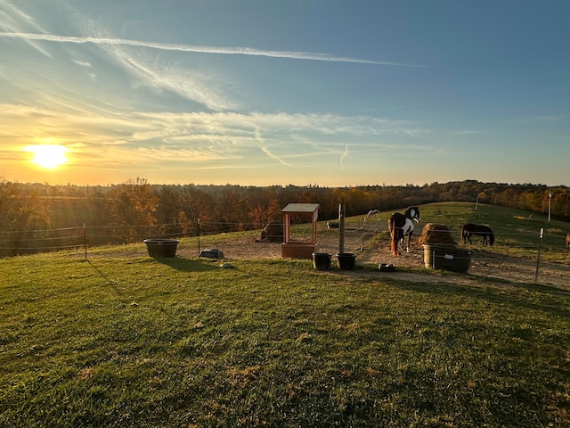 yard at dusk featuring a rural view