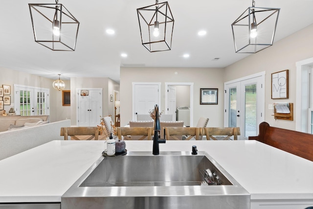 kitchen with french doors, light countertops, a sink, and open floor plan