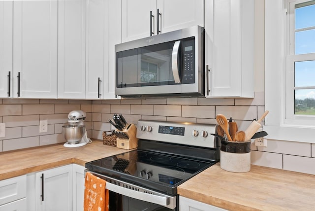 kitchen with stainless steel appliances, butcher block counters, backsplash, and white cabinetry