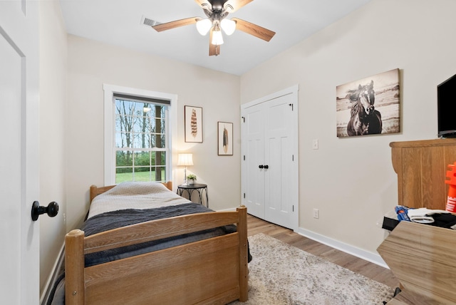 bedroom featuring a ceiling fan, visible vents, baseboards, and wood finished floors