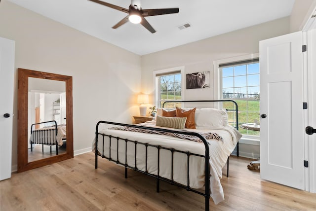 bedroom with light wood-type flooring, visible vents, baseboards, and multiple windows