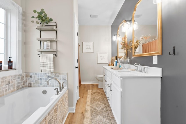 full bath with toilet, vanity, wood finished floors, baseboards, and a bath