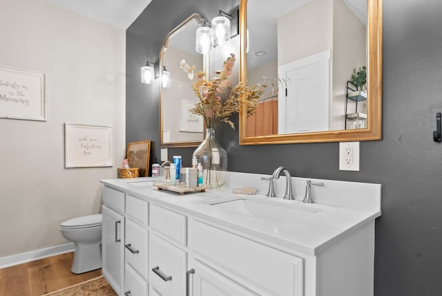 bathroom featuring double vanity, baseboards, a sink, and wood finished floors