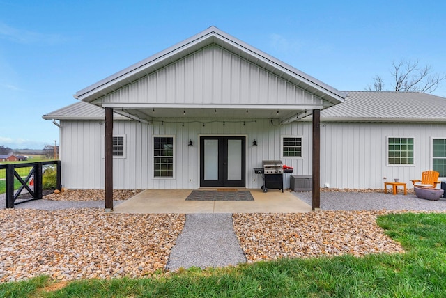 view of front of property with metal roof, french doors, board and batten siding, and a patio area