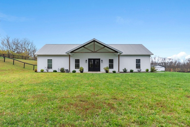 view of front facade featuring a front yard, french doors, fence, and metal roof