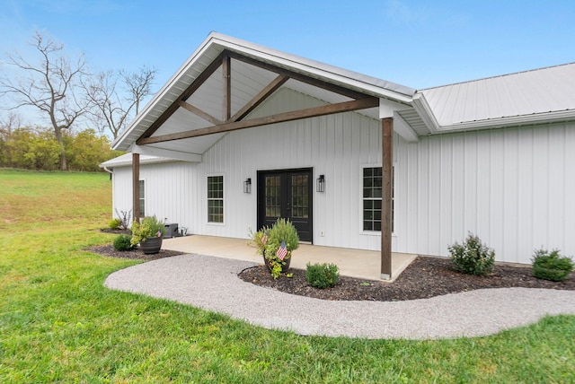 view of exterior entry featuring metal roof, a patio, french doors, and a lawn