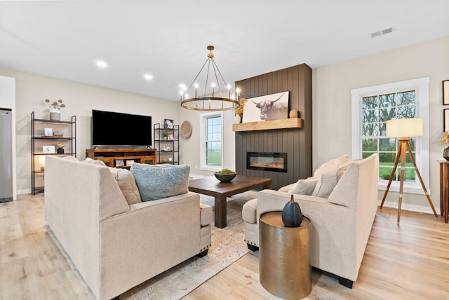 living area featuring light wood finished floors, a fireplace, and visible vents