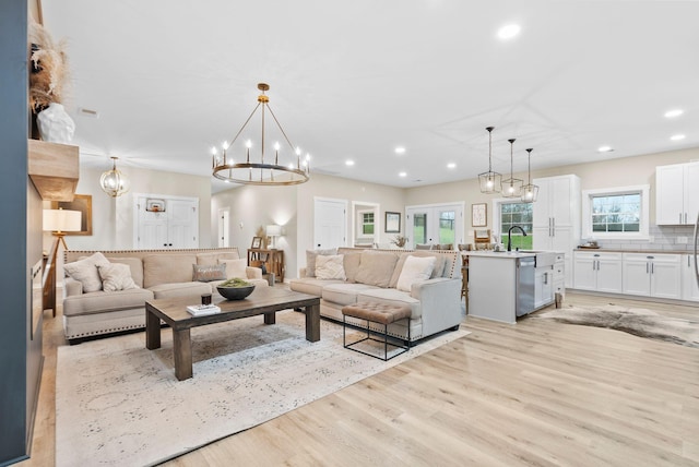 living room featuring light wood-style floors, french doors, an inviting chandelier, and recessed lighting