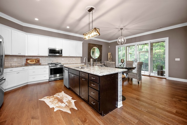 kitchen featuring hardwood / wood-style flooring, an island with sink, sink, pendant lighting, and appliances with stainless steel finishes