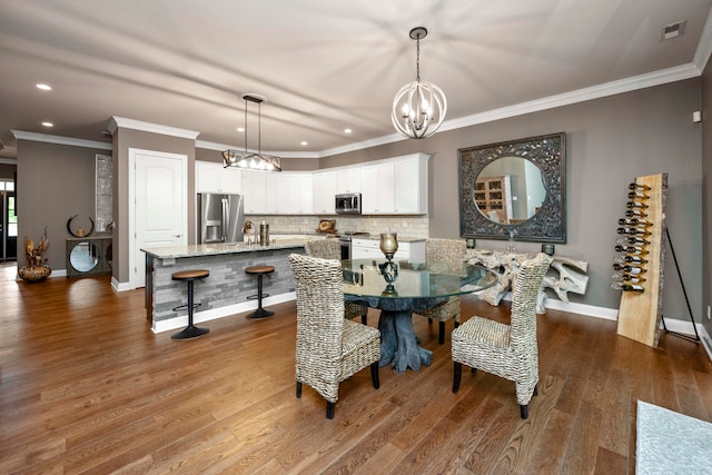 dining room with crown molding, a notable chandelier, wood-type flooring, and sink