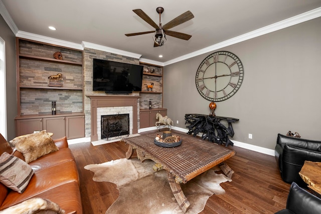 living room with dark wood-type flooring, crown molding, a fireplace, and ceiling fan