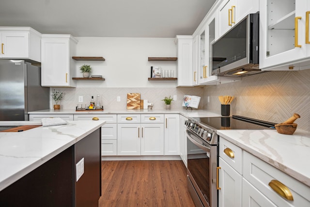 kitchen featuring white cabinets, tasteful backsplash, light stone countertops, dark wood-type flooring, and stainless steel appliances