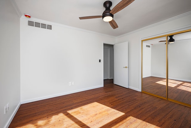 unfurnished bedroom featuring ornamental molding, a closet, dark hardwood / wood-style floors, and ceiling fan