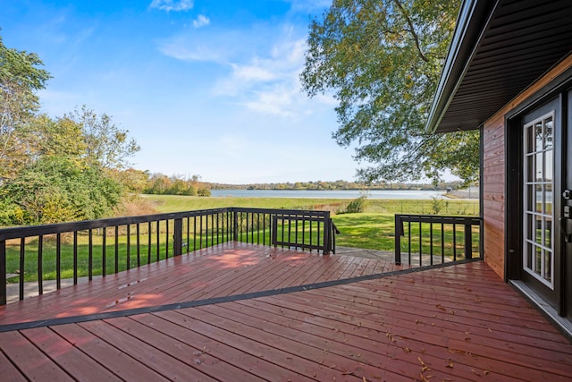 wooden terrace with a water view and a lawn