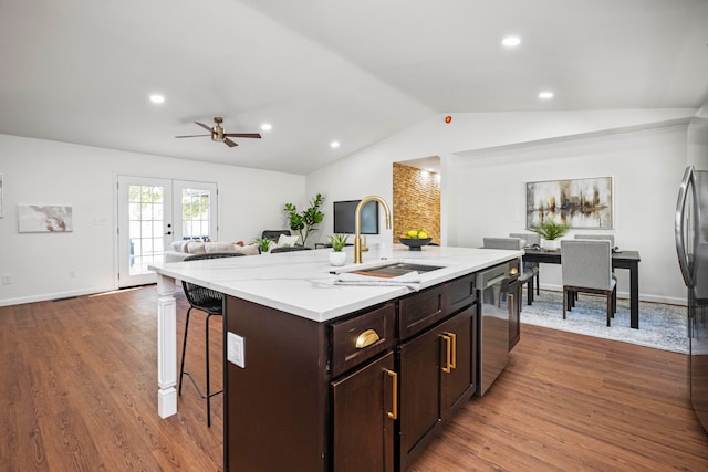 kitchen with lofted ceiling, dark hardwood / wood-style floors, a center island with sink, sink, and stainless steel dishwasher