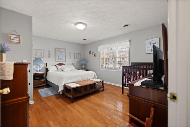 bedroom featuring a textured ceiling and light hardwood / wood-style flooring