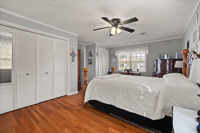 bedroom featuring ceiling fan, crown molding, two closets, and hardwood / wood-style floors