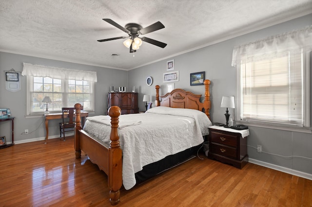 bedroom with ornamental molding, a textured ceiling, light wood-type flooring, and ceiling fan