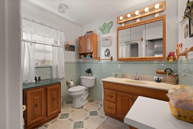 bathroom with tile walls, vanity, and toilet