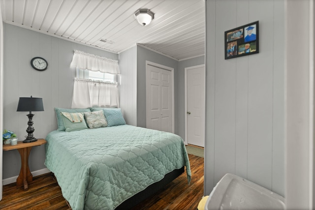 bedroom featuring dark wood-type flooring, wood walls, and ornamental molding